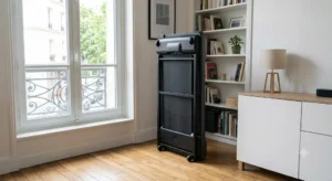 Rangement compact d'un tapis de course bureau pliant glissé verticalement pour optimiser l'espace.